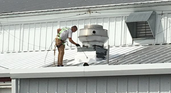 roofing pro spraying coating around hvac unit